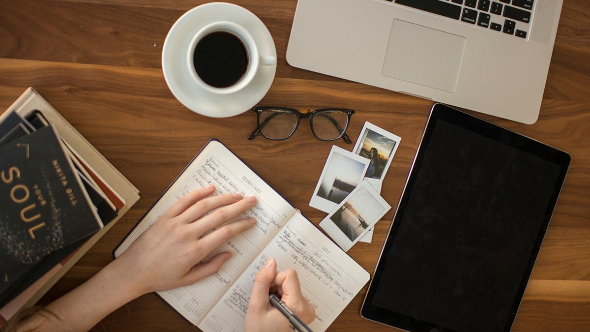 Photo of a writer's hands writing in a notebook.